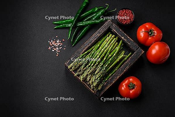 Food, Delicious fresh sprigs of asparagus on a dark textured background. Ingredients for a healthy vegetarian meal [IBR124842069]