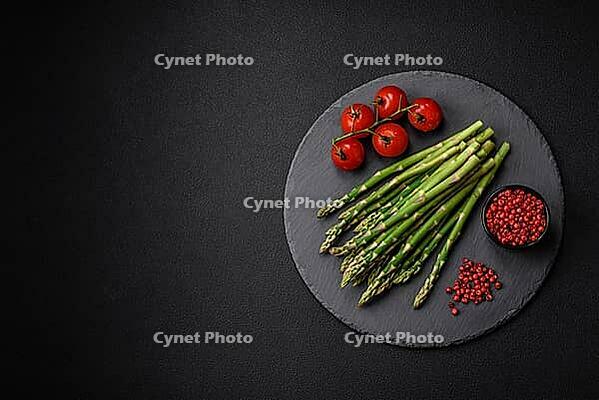 Food, Delicious fresh sprigs of asparagus on a dark textured background. Ingredients for a healthy vegetarian meal [IBR124842072]