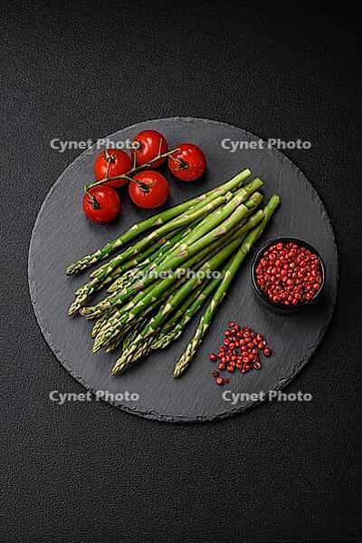 Food, Delicious fresh sprigs of asparagus on a dark textured background. Ingredients for a healthy vegetarian meal [IBR124842073]
