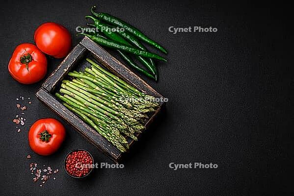 Food, Delicious fresh sprigs of asparagus on a dark textured background. Ingredients for a healthy vegetarian meal [IBR124842075]