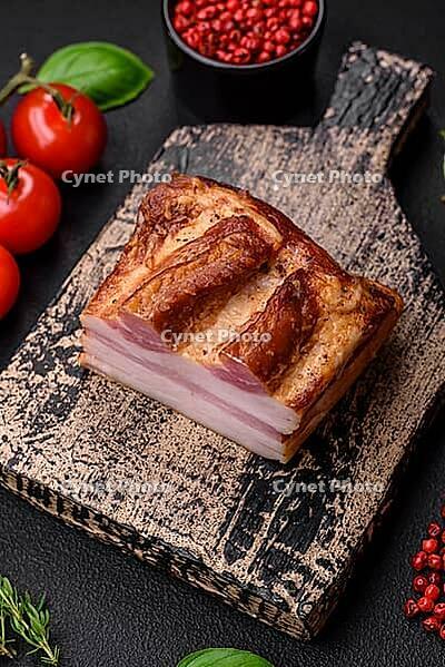 Food, Delicious calorie smoked bacon with salt, spices and herbs on a dark concrete background [IBR124842079]