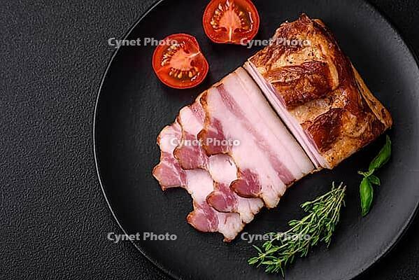 Food, Delicious calorie smoked bacon with salt, spices and herbs on a dark concrete background [IBR124842085]