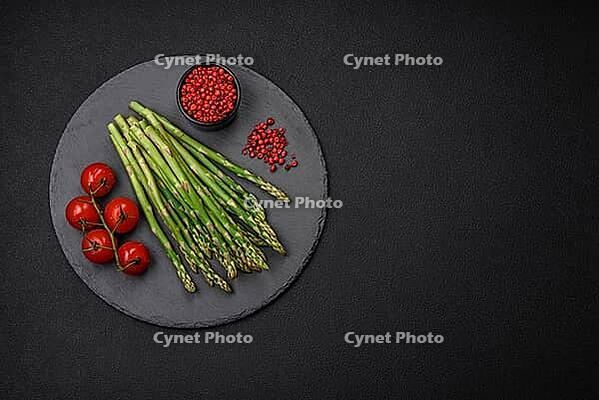Food, Delicious fresh sprigs of asparagus on a dark textured background. Ingredients for a healthy vegetarian meal [IBR124842086]