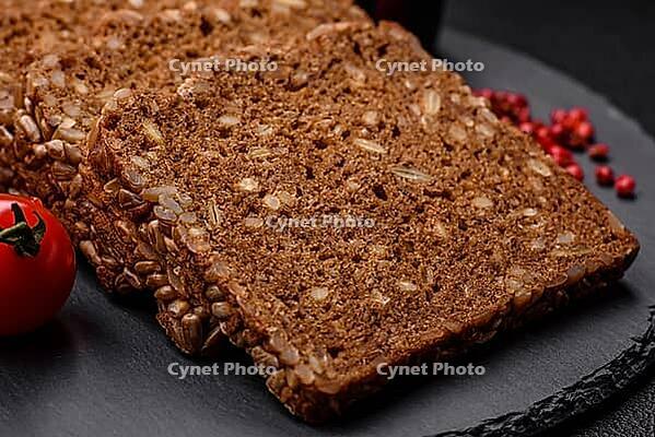 Food, Delicious fresh crispy brown bread with seeds and grains cut into slices on a dark concrete background [IBR124842087]