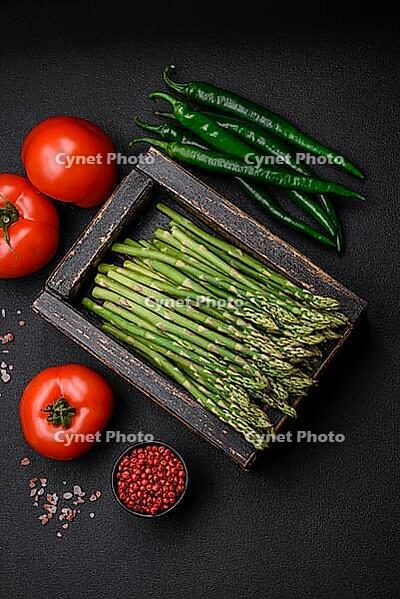 Food, Delicious fresh sprigs of asparagus on a dark textured background. Ingredients for a healthy vegetarian meal [IBR124842088]