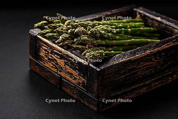 Food, Delicious fresh sprigs of asparagus on a dark textured background. Ingredients for a healthy vegetarian meal [IBR124842090]