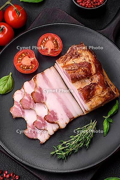 Food, Delicious calorie smoked bacon with salt, spices and herbs on a dark concrete background [IBR124842100]