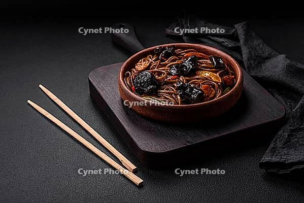 Food, Delicious fresh buckwheat noodles or udon with mushrooms, peppers and other vegetables, spices and herbs on a dark concrete background [IBR124842104]