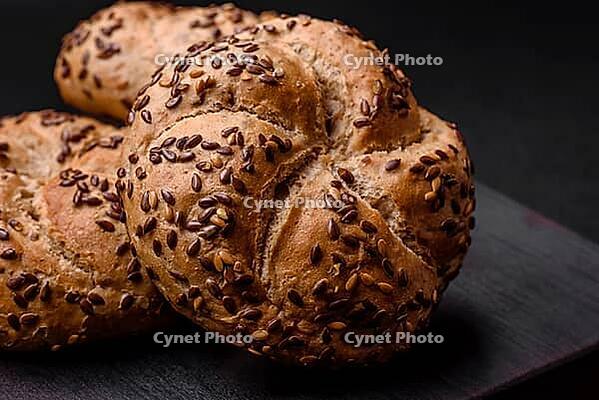 Food, Delicious freshly baked crispy bun or kaiser roll with sesame seeds on dark concrete background [IBR124842110]