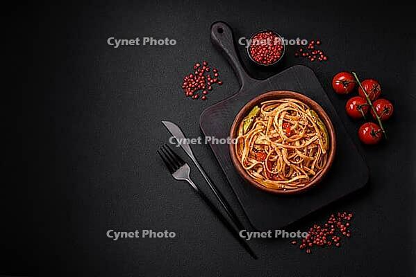 Food, Delicious asian udon dish with vegetables, mushrooms, salt and spices on a ceramic plate on a dark concrete background [IBR124842111]