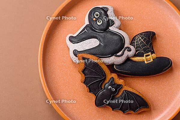 Halloween cookies, sweets, or gingerbread, a cat, a bat, and a hat. Halloween cookies as a backdrop for your design [IBR124865244]