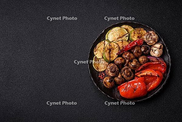 Grilled vegetables, bell peppers, mushrooms, and zucchini, a vegetarian healthy meal with sauce. Grilled vegetables on a plate as a food background for your design [IBR124865253]