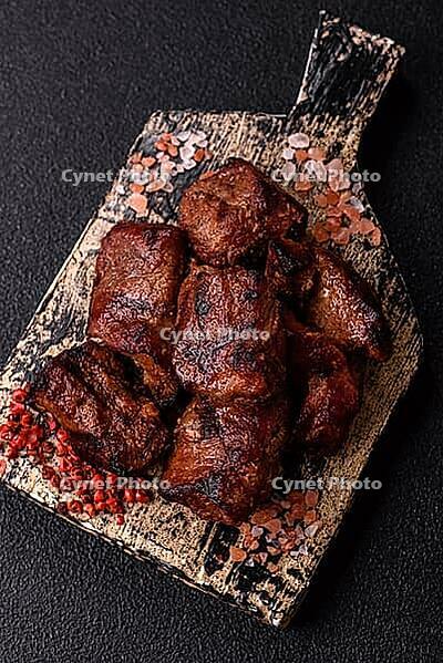 Beef, grilled meat in pieces, or kebab with sauce and vegetables. Beef in pieces as a food background for your design [IBR124865273]