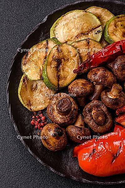 Grilled vegetables, bell peppers, mushrooms, and zucchini, a vegetarian healthy meal with sauce. Grilled vegetables on a plate as a food background for your design [IBR124865283]