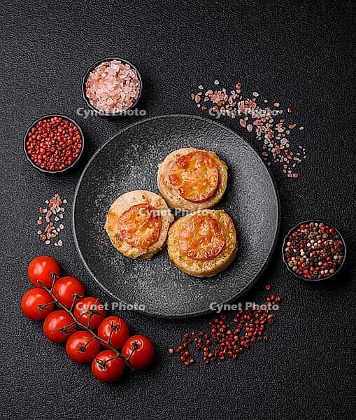 Round fish or chicken cutlets baked with tomato and cheese. Fish cutlets as a food backdrop for your design [IBR124865291]