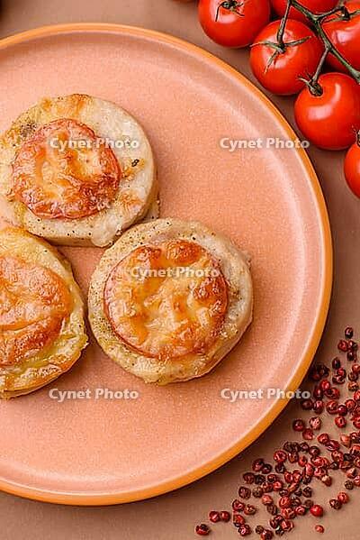 Round fish or chicken cutlets baked with tomato and cheese. Fish cutlets as a food backdrop for your design [IBR124865292]