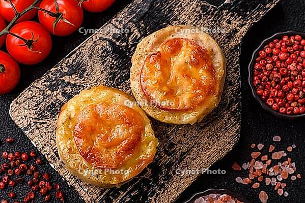 Round fish or chicken cutlets baked with tomato and cheese. Fish cutlets as a food backdrop for your design [IBR124865294]