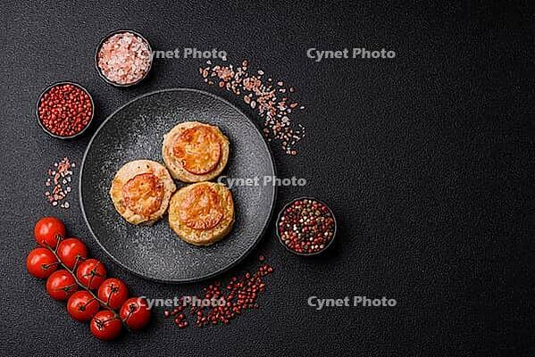 Round fish or chicken cutlets baked with tomato and cheese. Fish cutlets as a food backdrop for your design [IBR124865308]