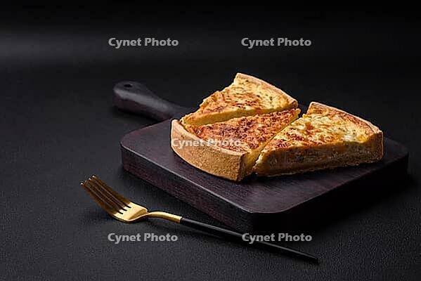 Food, Beautiful delicious quiche pie with four types of cheese with spices and herbs on a dark concrete background [IBR124876427]