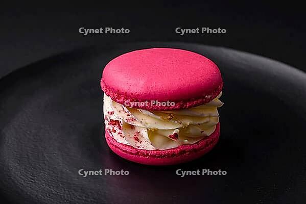 Food, Beautiful tasty macaron with filling and fruit flavor on a black plate on a dark concrete background [IBR124876429]