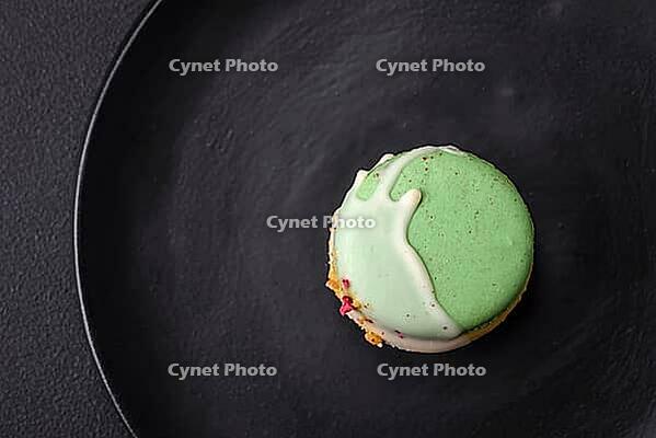 Food, Beautiful tasty macaron with filling and fruit flavor on a black plate on a dark concrete background [IBR124876430]