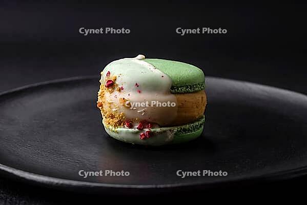Food, Beautiful tasty macaron with filling and fruit flavor on a black plate on a dark concrete background [IBR124876435]