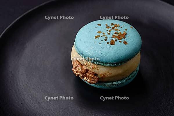 Food, Beautiful tasty macaron with filling and fruit flavor on a black plate on a dark concrete background [IBR124876437]