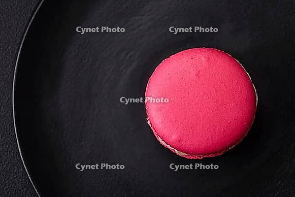 Food, Beautiful tasty macaron with filling and fruit flavor on a black plate on a dark concrete background [IBR124876438]