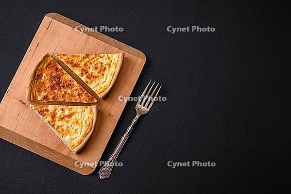 Food, Beautiful delicious quiche pie with four types of cheese with spices and herbs on a dark concrete background [IBR124876441]