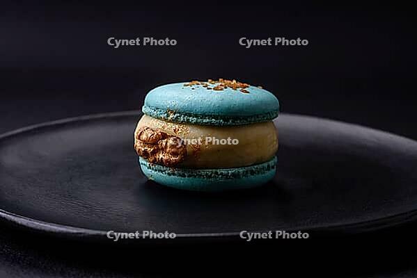 Food, Beautiful tasty macaron with filling and fruit flavor on a black plate on a dark concrete background [IBR124876445]