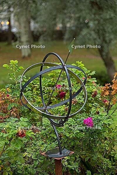 Armillary sphere, which also functions as a sundial or sun clock in a garden surrounded by plants in summer, Loviisa, Finland [IBR124899516]