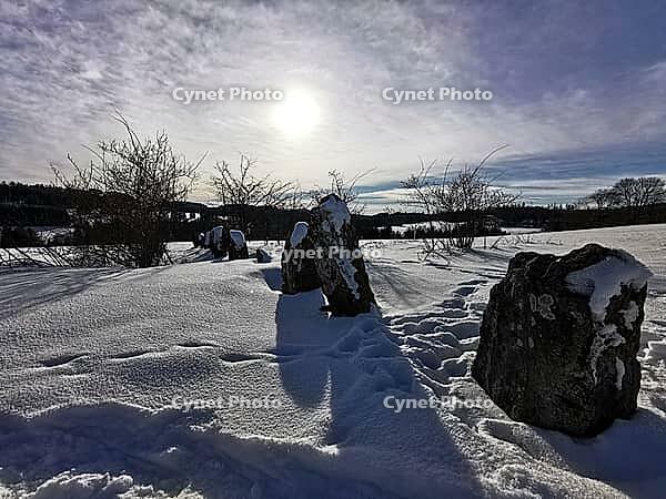 Snowy landscape with sunlit stones, clouds and an extensive field, hiking in winter, Frankenwaldsteigla, 12 Apostle Trail, Frankenwald nature park Park, Upper Franconia [IBR124899545]