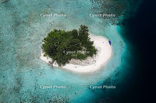 Aerial view from top to bottom of a small tropical island with white sandy beach and a boat and a presented reef, Raja Ampat, West Papua, Indonesia [IBR124899548]