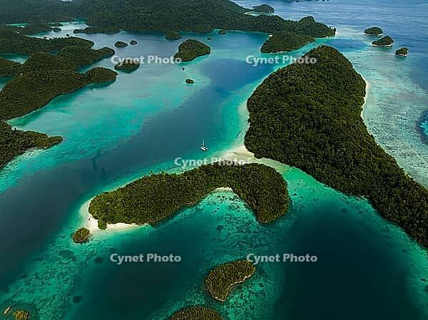 Aerial view of many small tropical islands with turquoise water and presented reefs and a sailing catamaran, Pulau Wayag, Raja Ampat, West Papua, Indonesia [IBR124899550]