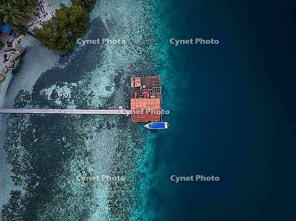 Aerial view from top to bottom of a jetty and a boat and a presented reef, Raja Ampat, West Papua, Indonesia [IBR124899552]
