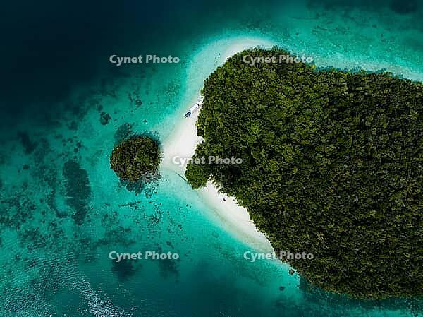 Aerial view from top to bottom of a small tropical island with turquoise water, white sandy beach and a boat, Pulau Wayag, Raja Ampat, West Papua, Indonesia [IBR124899556]