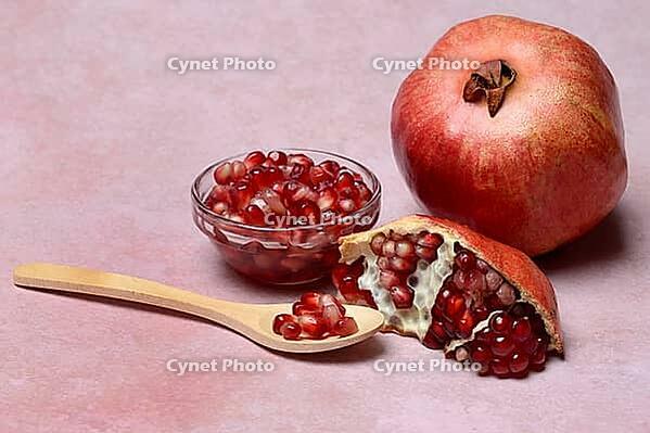 Opened pomegranate and pomegranate seeds in bowl and spoon, Punica granatum [IBR124899846]