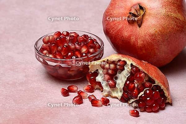 Opened pomegranate and pomegranate seeds in skin, Punica granatum [IBR124899847]