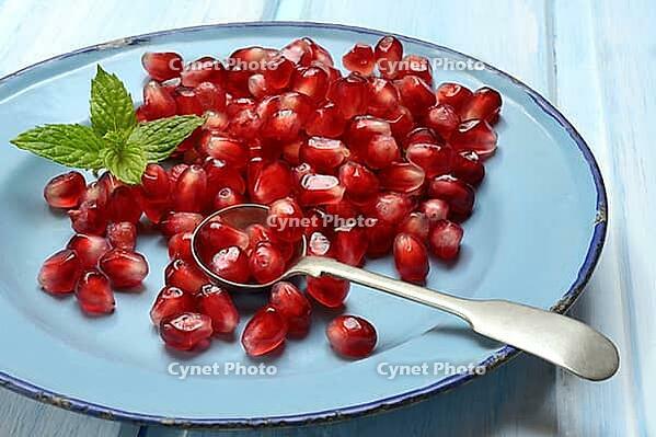 Pomegranate seeds and spoons on plate, Punica granatum [IBR124899851]