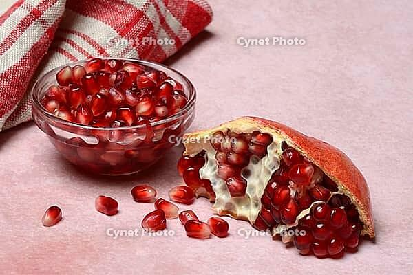 Opened pomegranate and pomegranate seeds in skin, Punica granatum [IBR124899854]