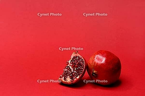 Pomegranate with red background, Punica granatum, cut in half [IBR124899855]