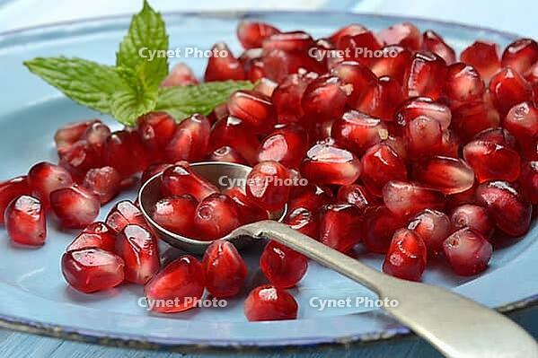 Pomegranate seeds and spoons on plate, Punica granatum [IBR124899856]