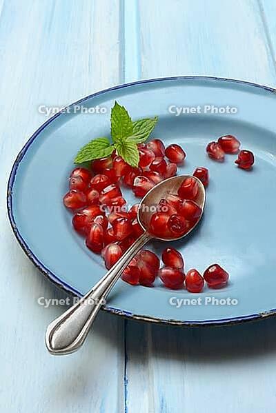 Pomegranate seeds and spoons on plate, Punica granatum [IBR124899858]