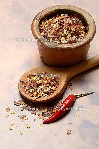 Chilli, chilli flakes in cooking spoon and pot, Capsicum annuum [IBR124899859]