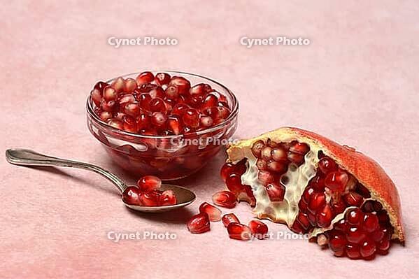 Opened pomegranate and pomegranate seeds in bowl and spoon, Punica granatum [IBR124899861]