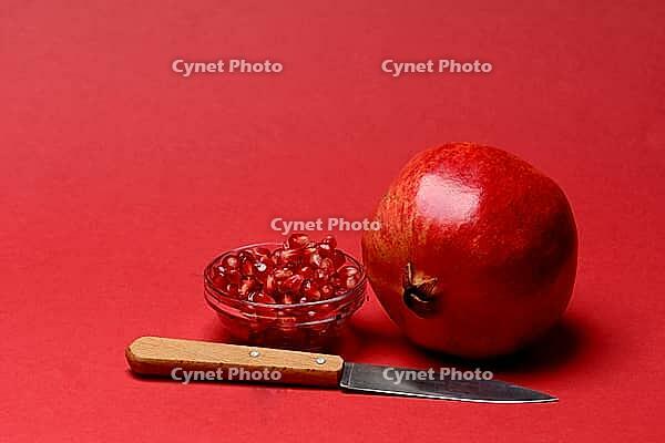 Pomegranate with red background, Punica granatum, cut in half [IBR124899862]
