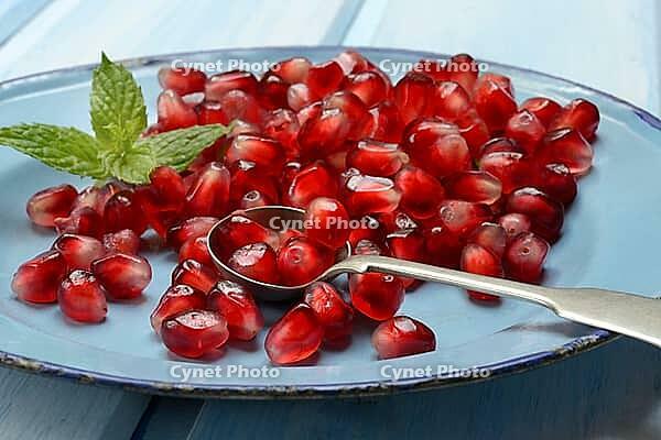 Pomegranate seeds and spoons on plate, Punica granatum [IBR124899865]