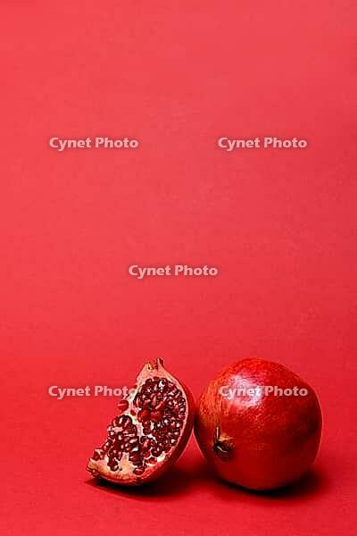 Pomegranate with red background, Punica granatum, cut in half [IBR124899871]