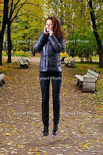 Woman soaring over a path in autumn park [IBR124906337]