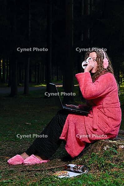 Happy woman is working on laptop at forest in undress [IBR124906338]